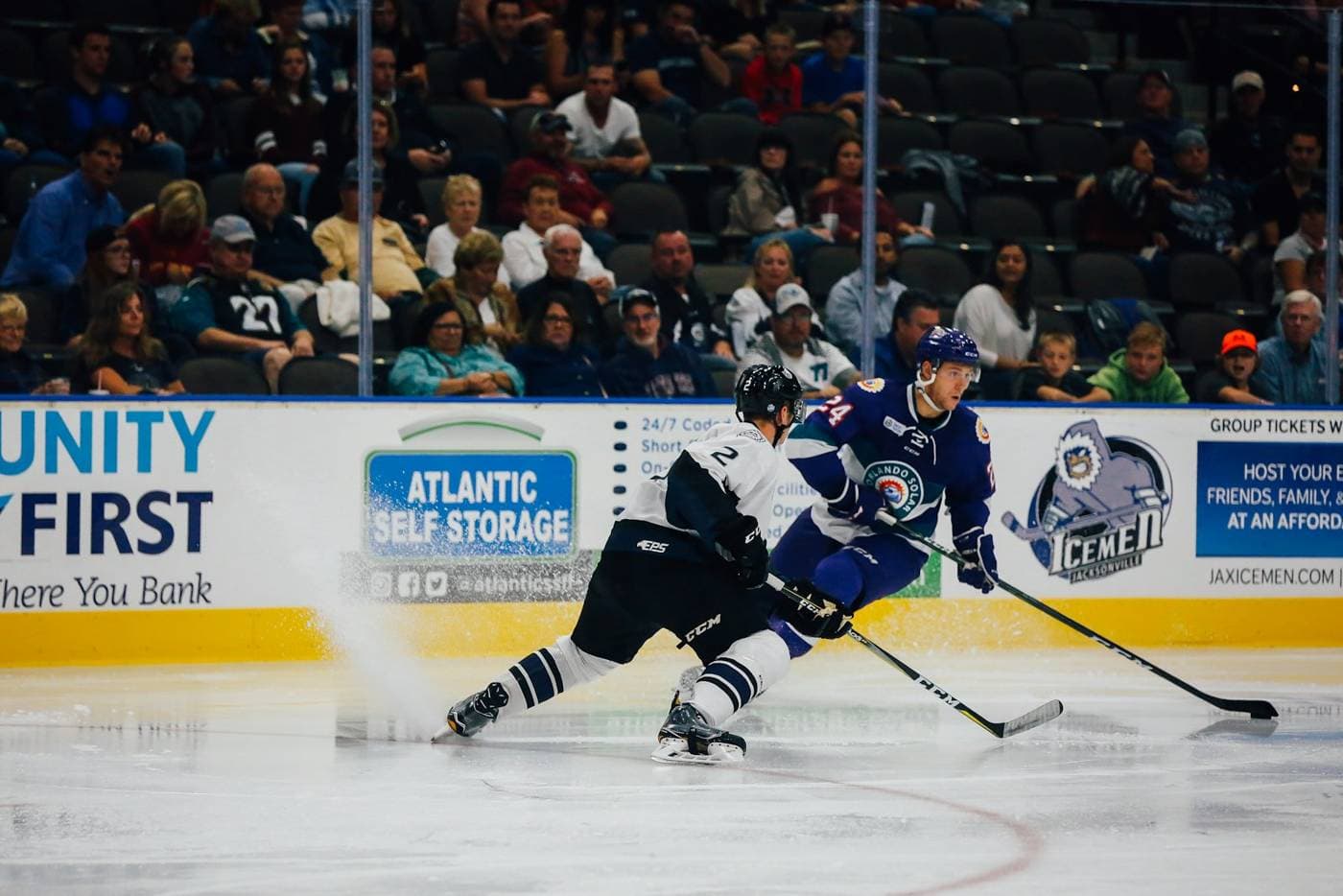 Players racing for the puck in front of a crowd